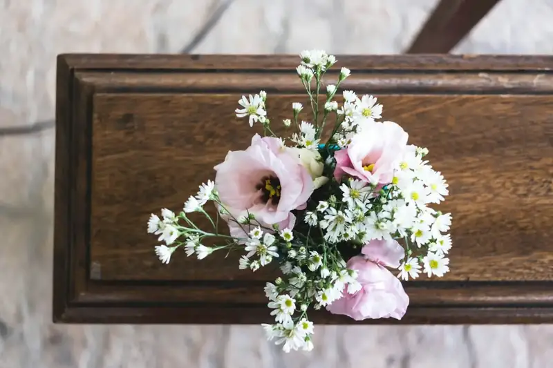 Pink and white flowers resting on a wooden coffin