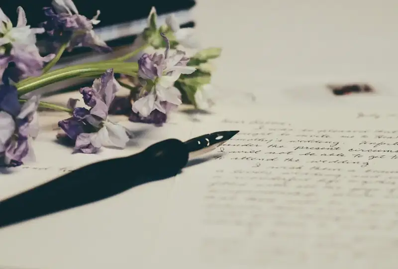 Handwritten letter and fountain pen beside flowers