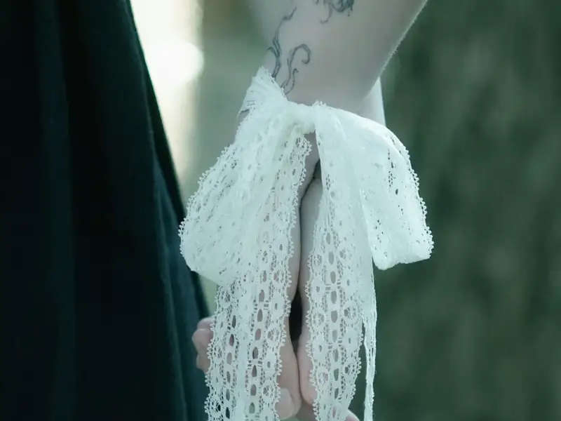 Couple’s clasped hands bound with white lace