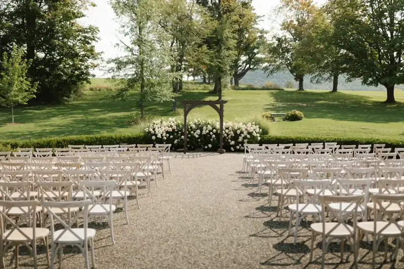 Rows of white chairs set up for an outdoor ceremony by a lake