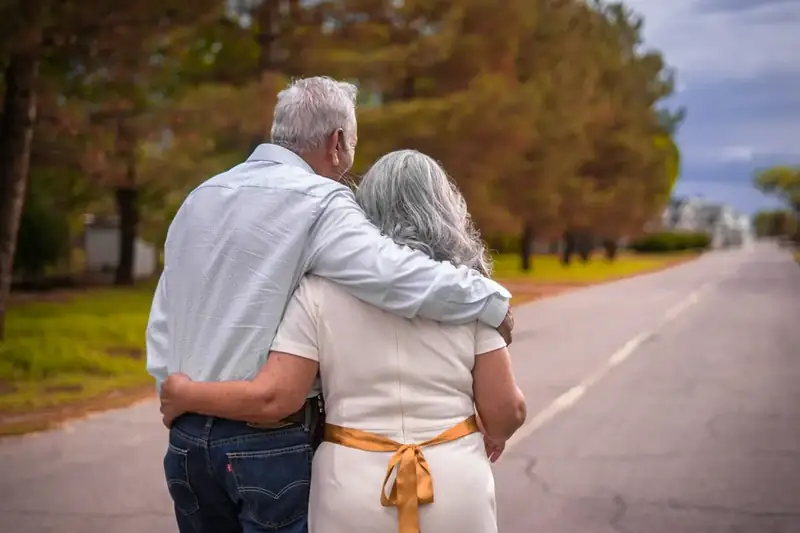 Older couple walking arm in arm down a country road