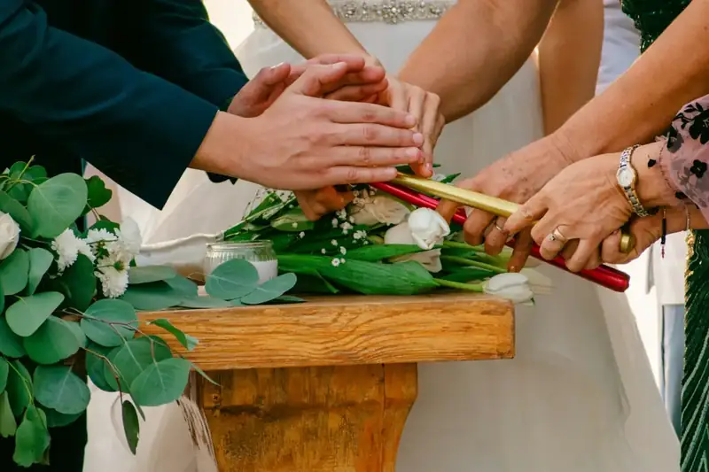 Hands lighting unity candles during a wedding ceremony