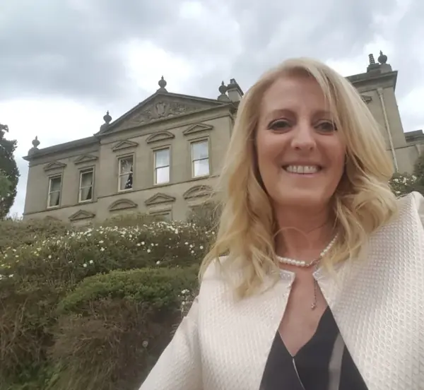 Hayley, independent celebrant in Leicestershire, smiling outside a country house