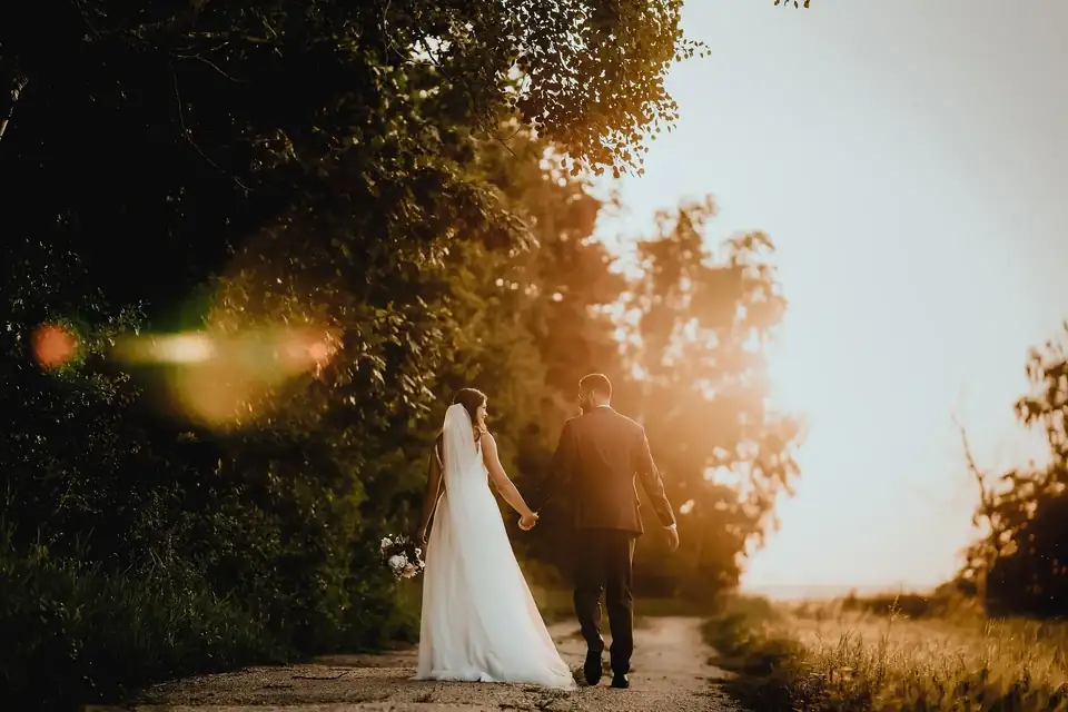 Couple walking hand in hand down a country lane at sunset
